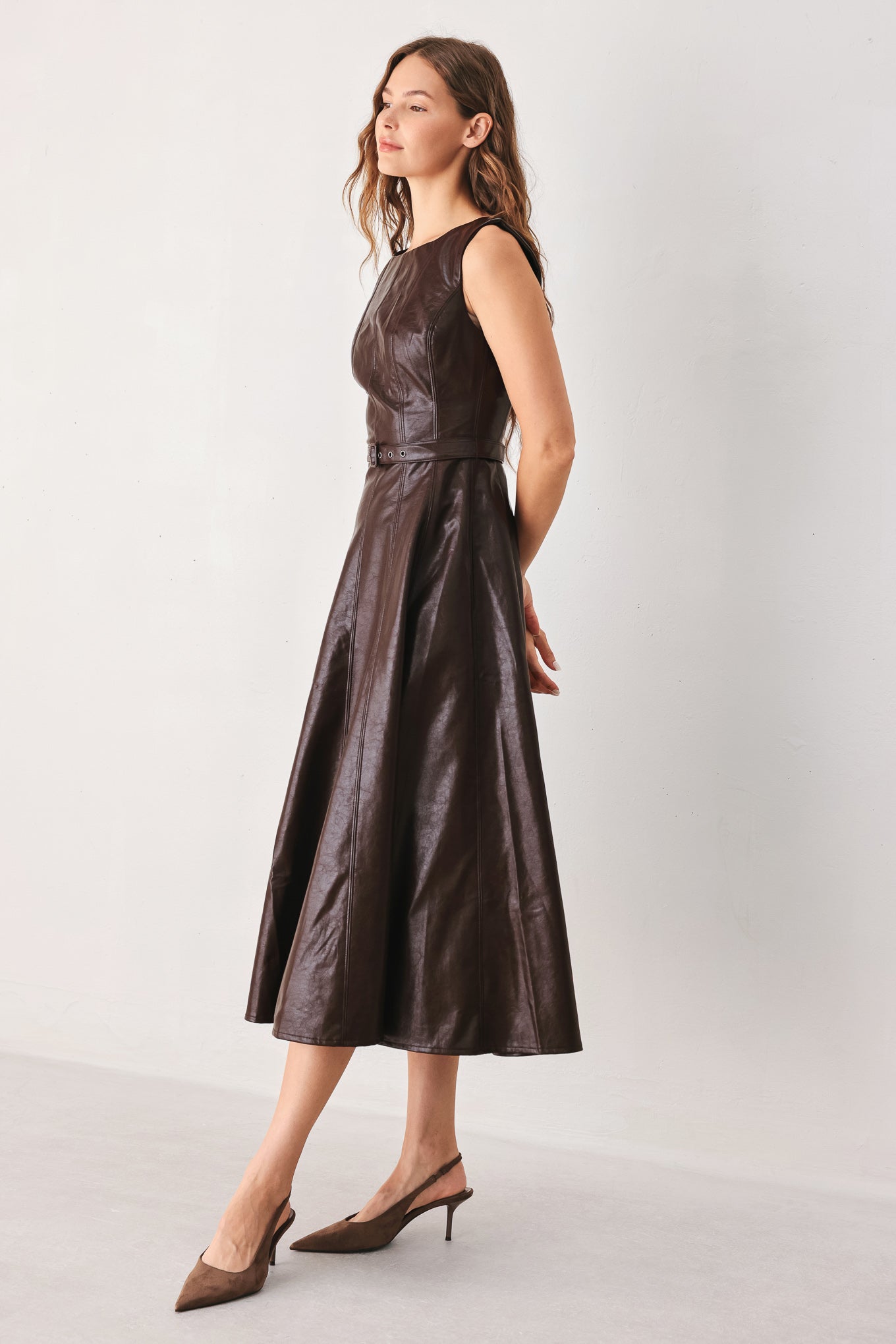 A woman wearing a sleeveless, dark brown faux-leather midi dress with a defined waist belt and a flared skirt | FREEMARKET