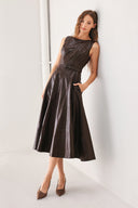 A woman wearing a sleeveless, dark brown faux-leather midi dress with a defined waist belt and a flared skirt | FREEMARKET
