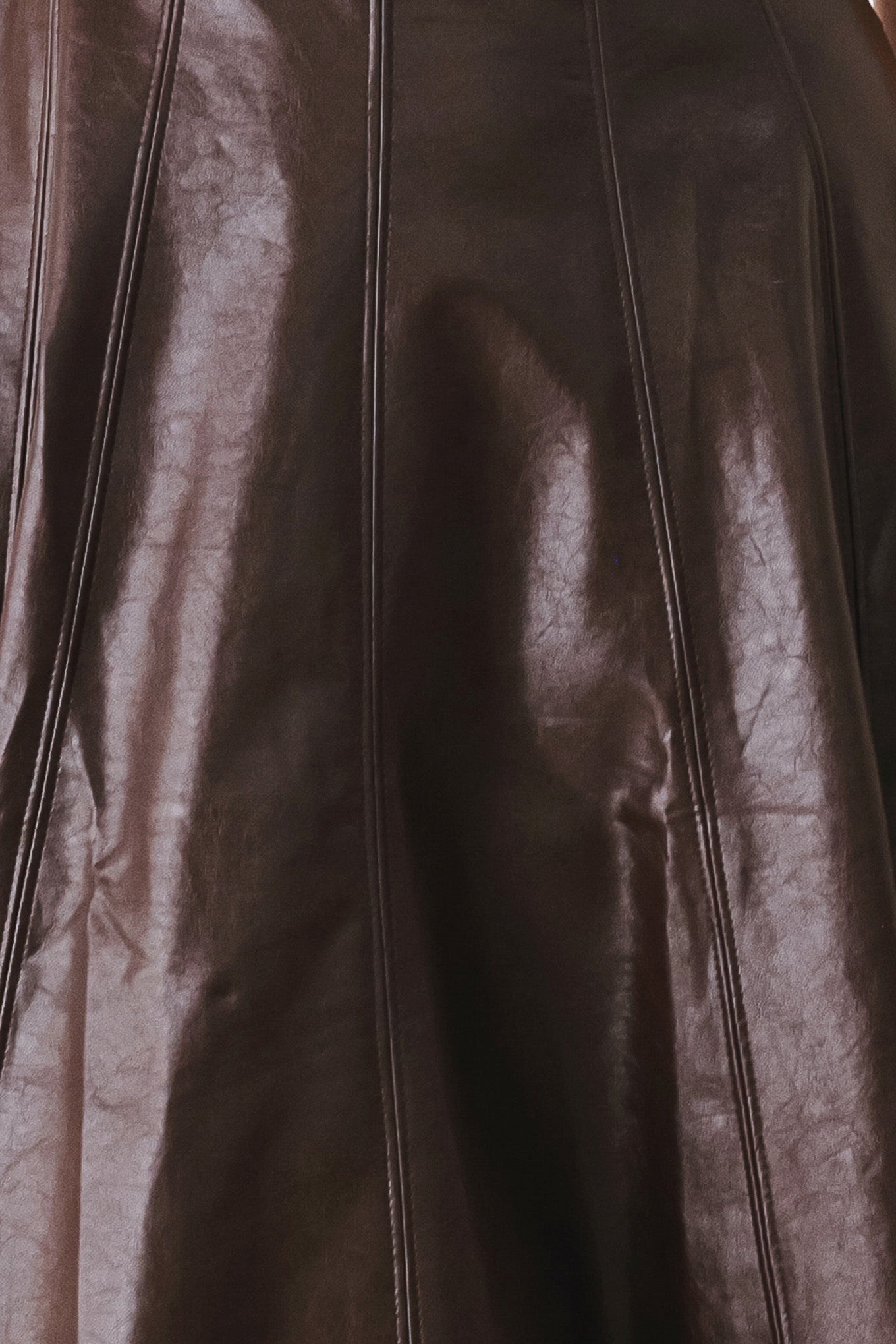 A woman wearing a sleeveless, dark brown faux-leather midi dress with a defined waist belt and a flared skirt | FREEMARKET