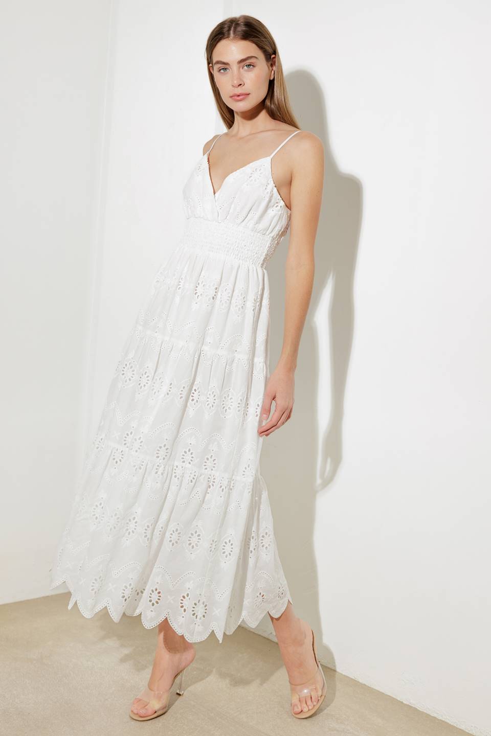 A woven eyelet midi dress featuring surplice cami top with adjustable straps, smocked waistband and tiered skirt