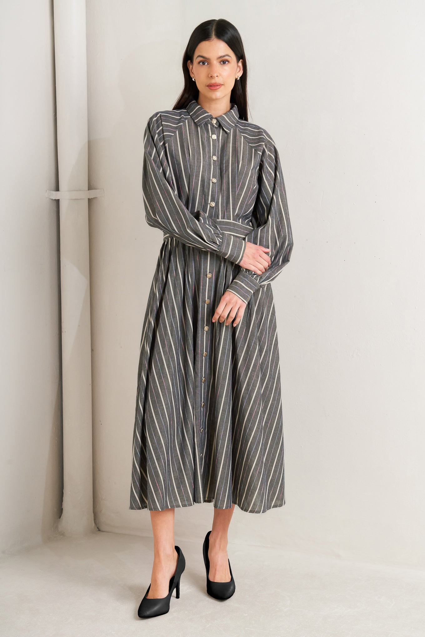 Woman wearing a striped dress standing against a white wall - Flying Tomato