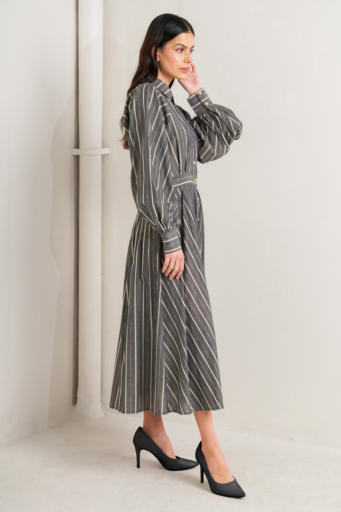Woman wearing a striped dress standing against a white wall - Flying Tomato