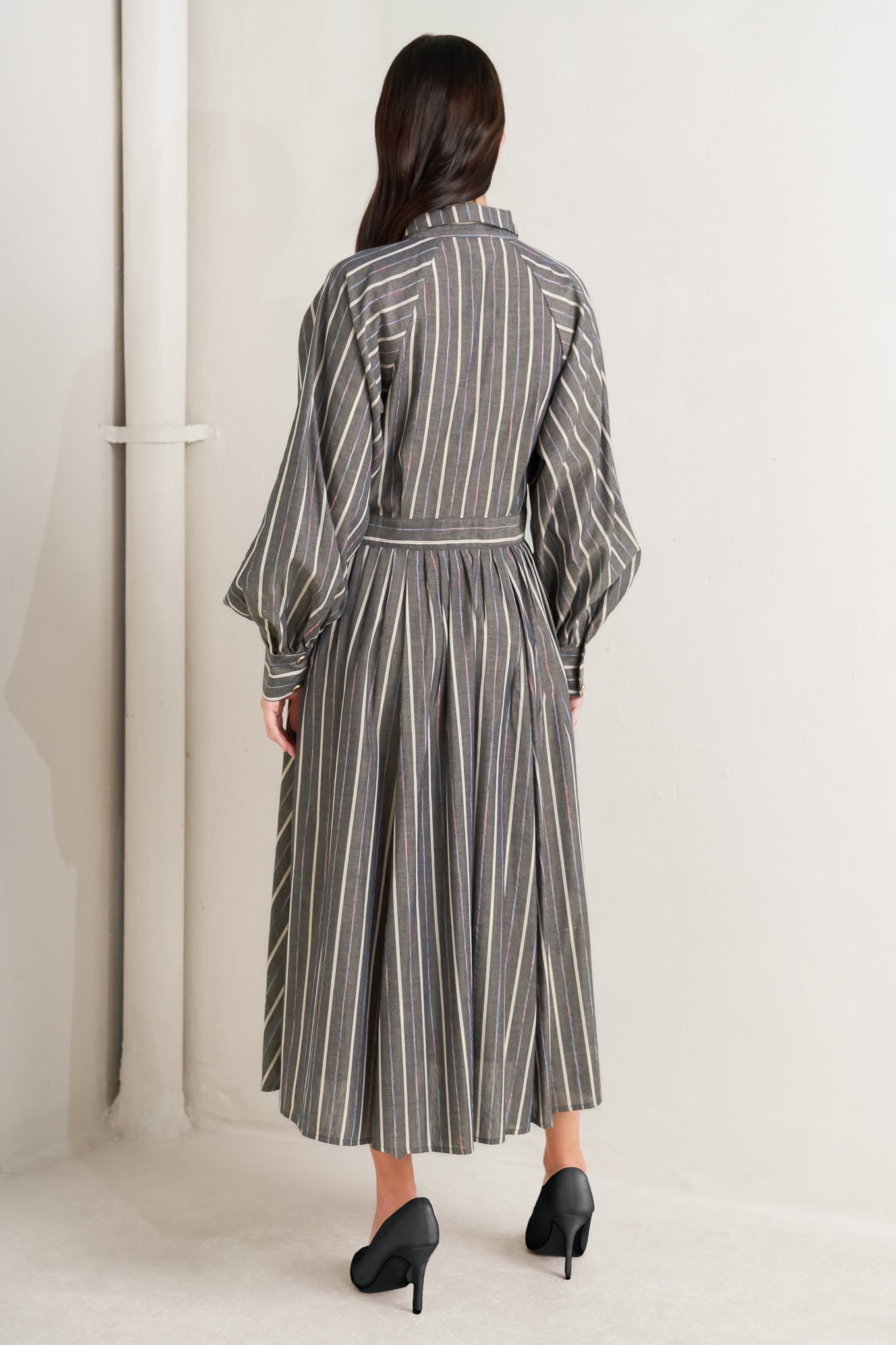 Woman wearing a striped dress standing against a white wall - Flying Tomato