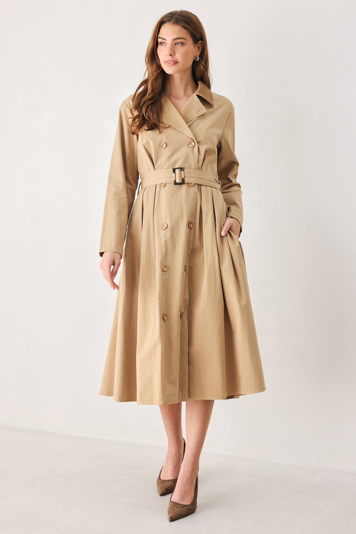 A woman models a beige double-breasted trench coat with a matching waist belt, paired with brown pointed-toe heels | FREEMARKET