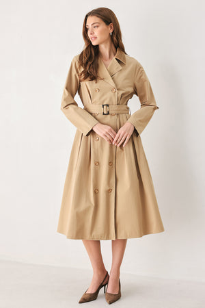 A woman models a beige double-breasted trench coat with a matching waist belt, paired with brown pointed-toe heels | FREEMARKET