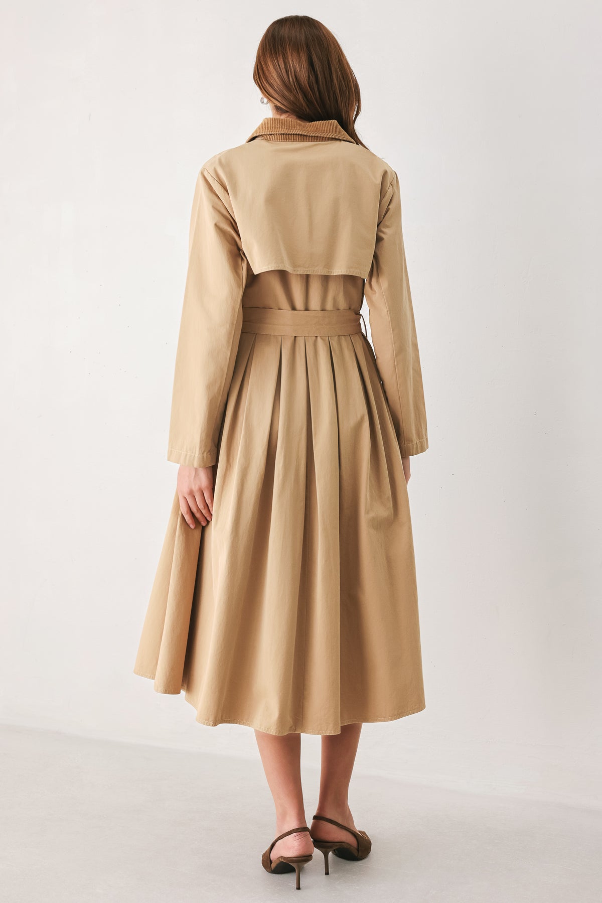 A woman models a beige double-breasted trench coat with a matching waist belt, paired with brown pointed-toe heels | FREEMARKET