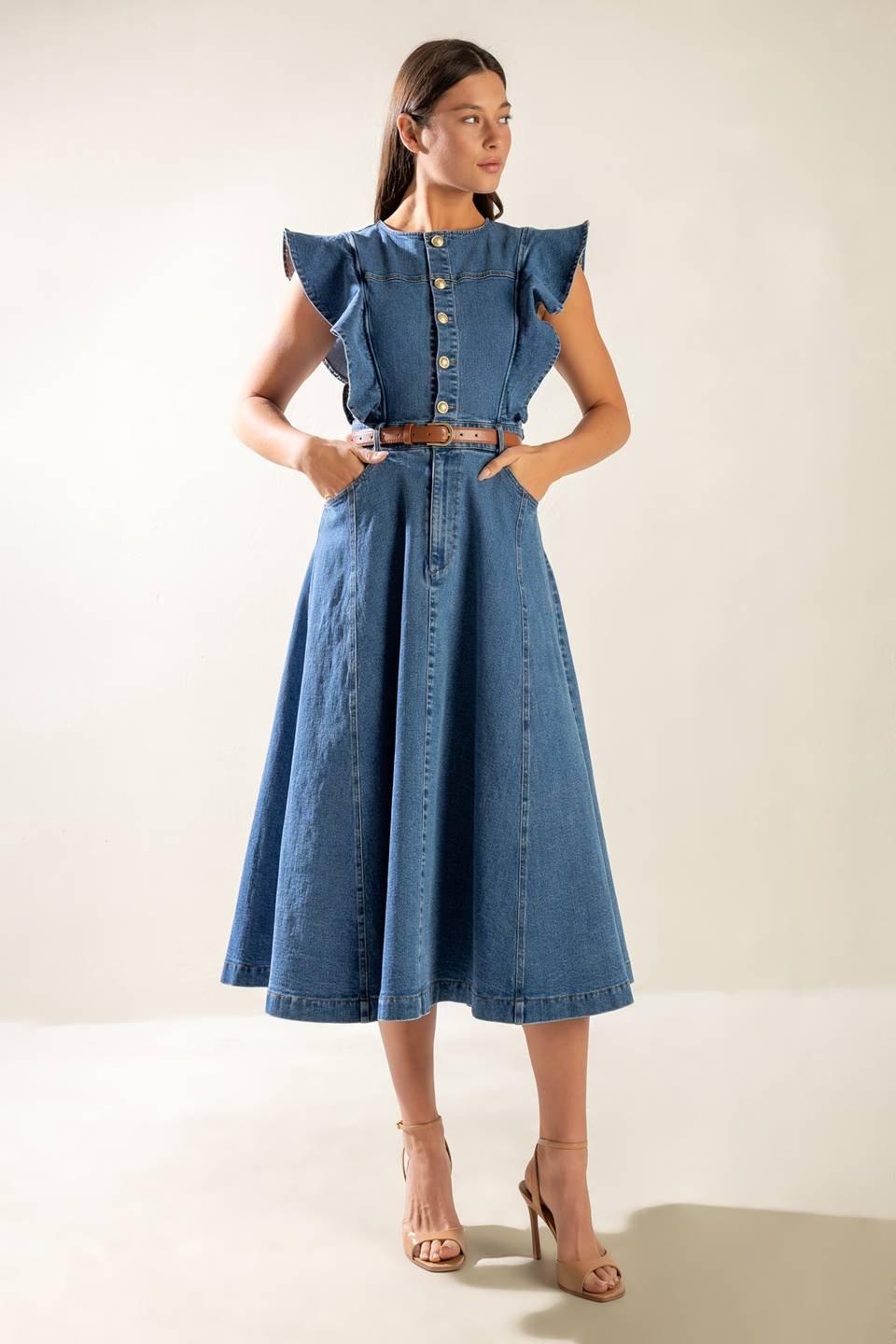 A washed blue denim midi dress featuring round neckline, short ruffled sleeve, front button/zipper closure, side pockets and full skirt.