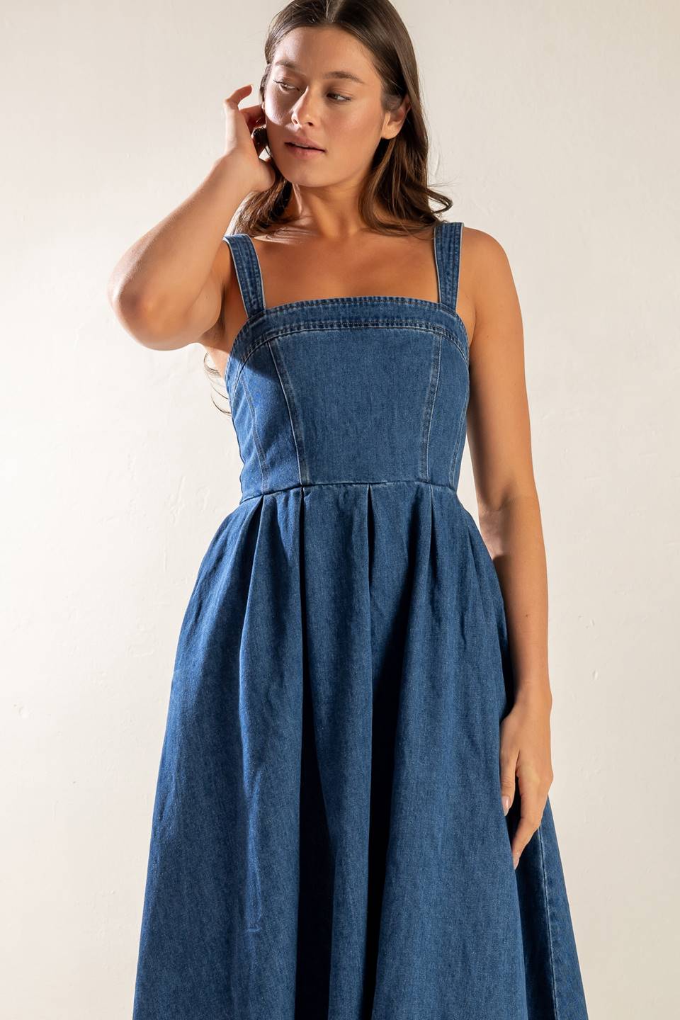 A washed denim midi dress featuring straight neckline, straps, inverted pleat full skirt and back zipper closure.