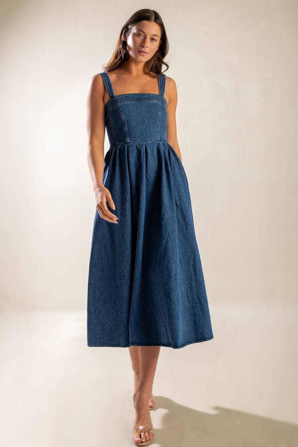 A washed denim midi dress featuring straight neckline, straps, inverted pleat full skirt and back zipper closure.