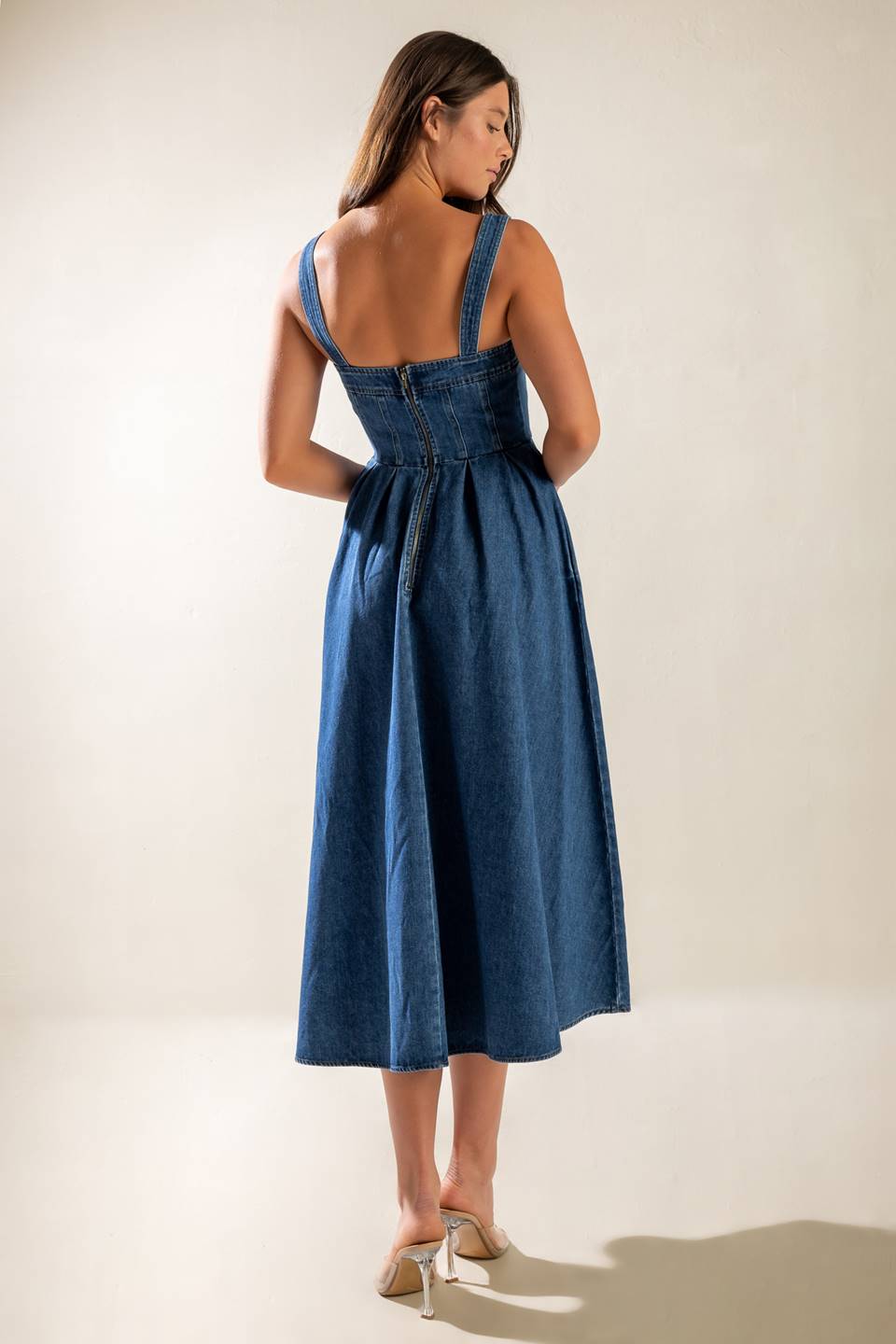 A washed denim midi dress featuring straight neckline, straps, inverted pleat full skirt and back zipper closure.