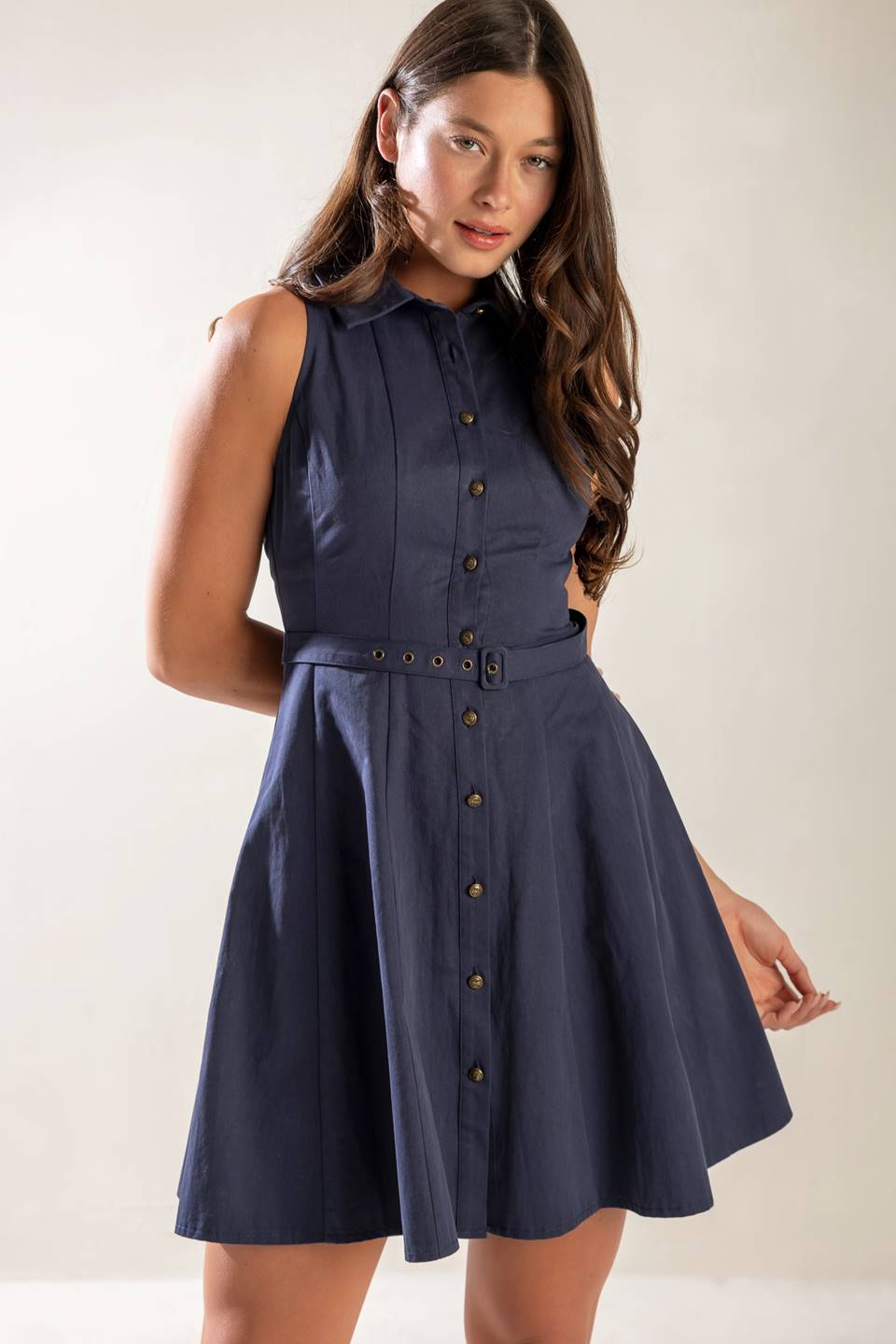 A sleeveless, solid navy woven mini dress featuring collar, button down, self belt and full skirt.