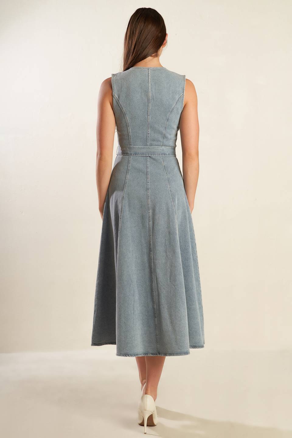 A sleeveless, washed light denim midi dress featuring round neckline, button down, self sash tie, side pockets and full skirt.