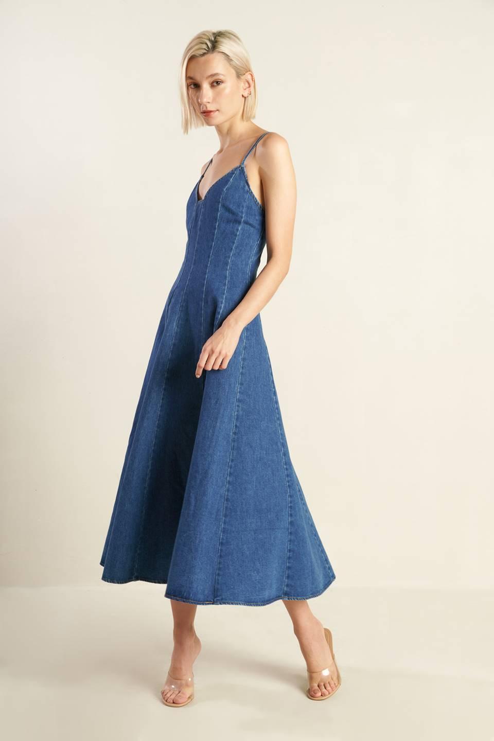 A washed denim dress featuring cami top with straps, fitted waist, side pockets, full skirt and back zipper closure