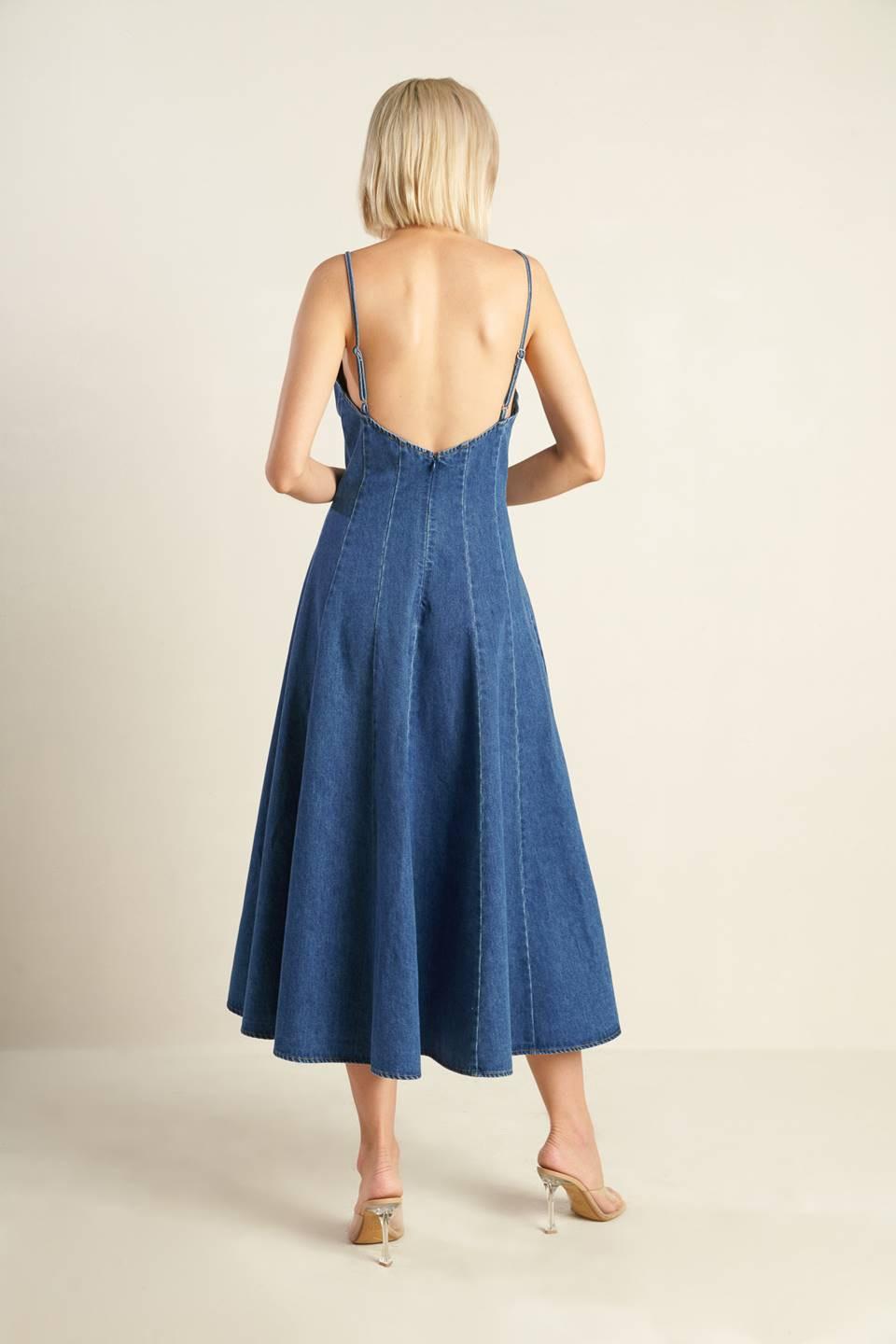 A washed denim dress featuring cami top with straps, fitted waist, side pockets, full skirt and back zipper closure