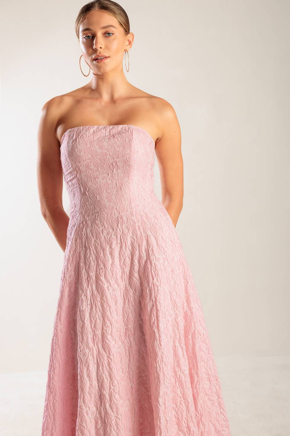 A textured pink woven midi dress featuring strapless, circle skirt and smocked back bodice with zipper closure