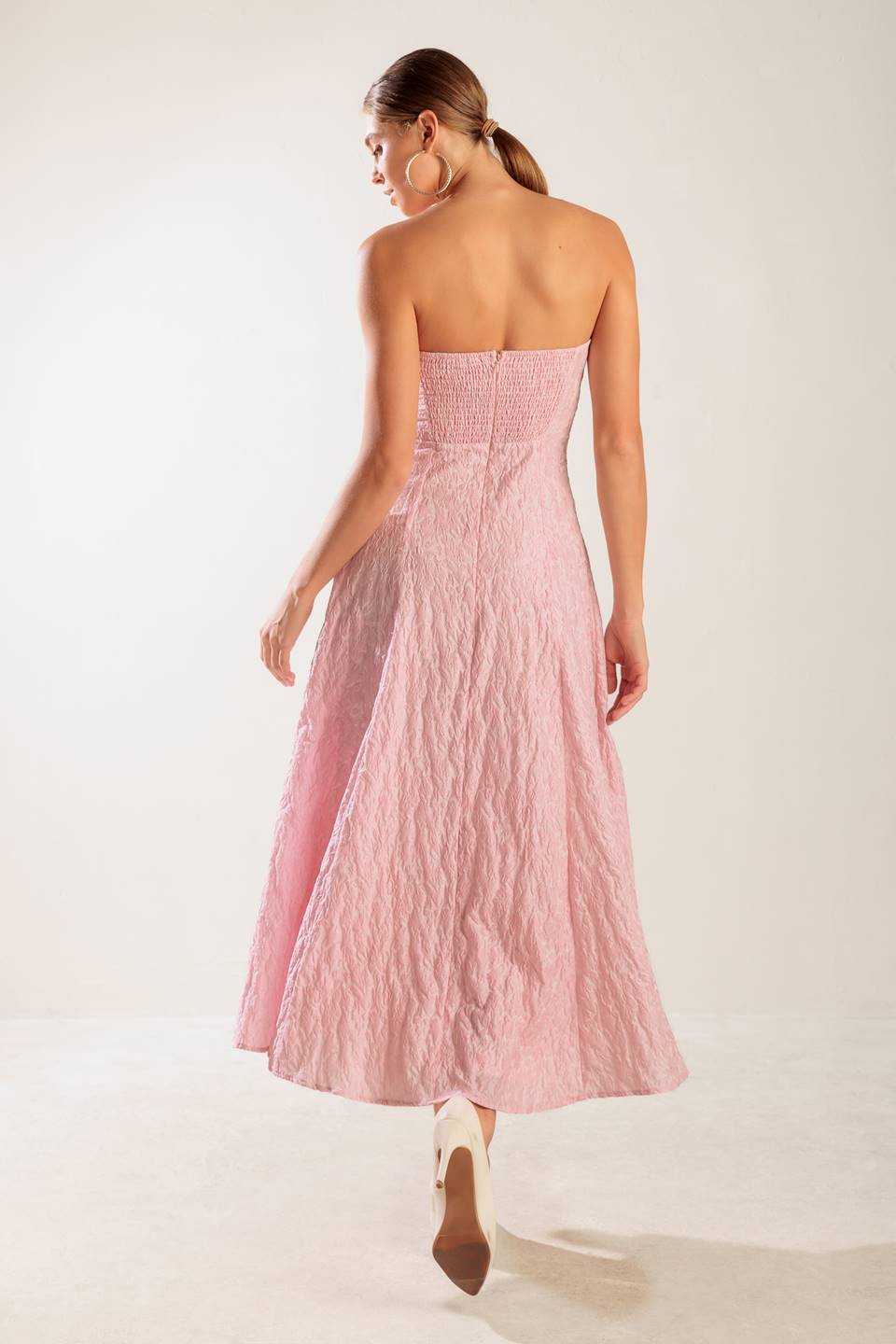 A textured pink woven midi dress featuring strapless, circle skirt and smocked back bodice with zipper closure