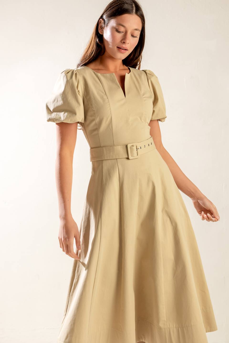 A solid woven midi dress featuring round neckline with V center, short puff sleeve, self belt, circle skirt and back zipper closure