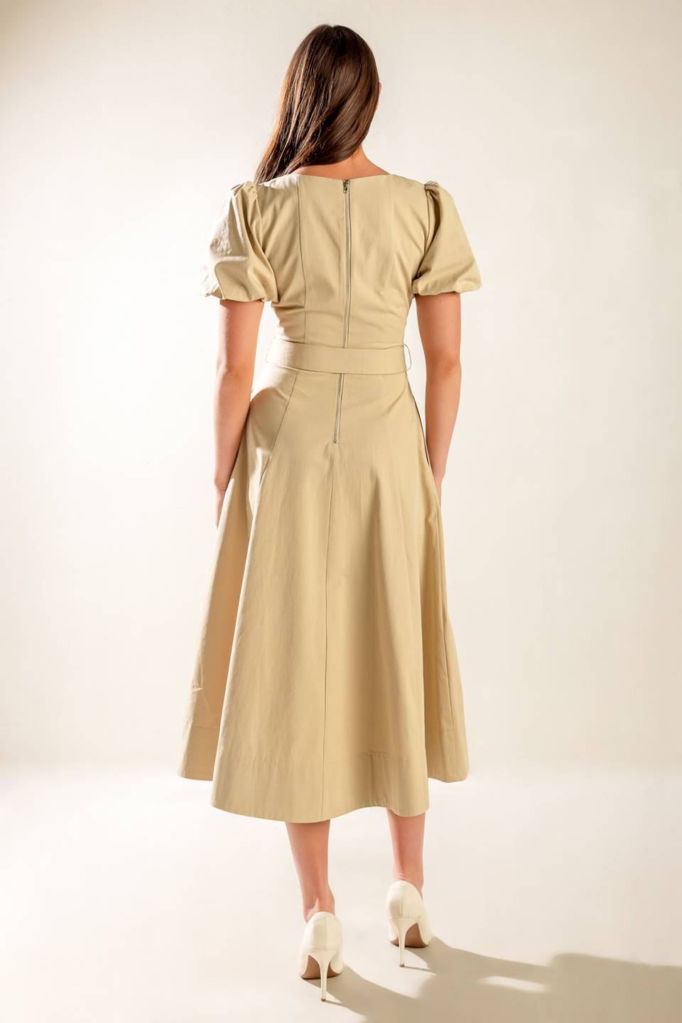 A solid woven midi dress featuring round neckline with V center, short puff sleeve, self belt, circle skirt and back zipper closure