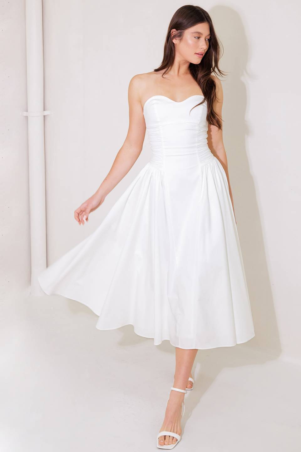 A white solid woven midi dress featuring sweetheart strapless neckline, shirred side full skirt and back zipper closure