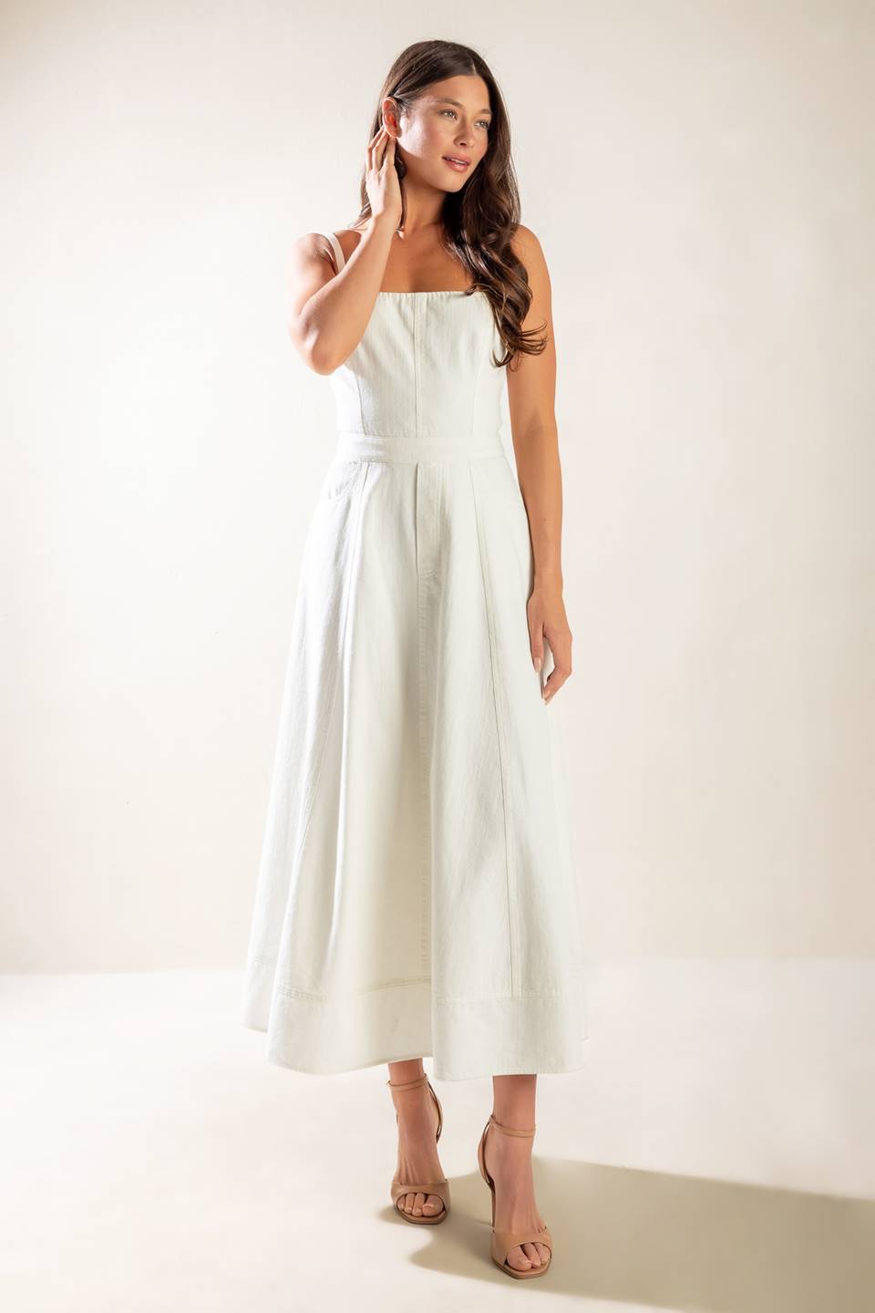 A solid white woven midi dress featuring straight neckline, straps, side pockets, circle skirt, bare back with tie and zipper closure.