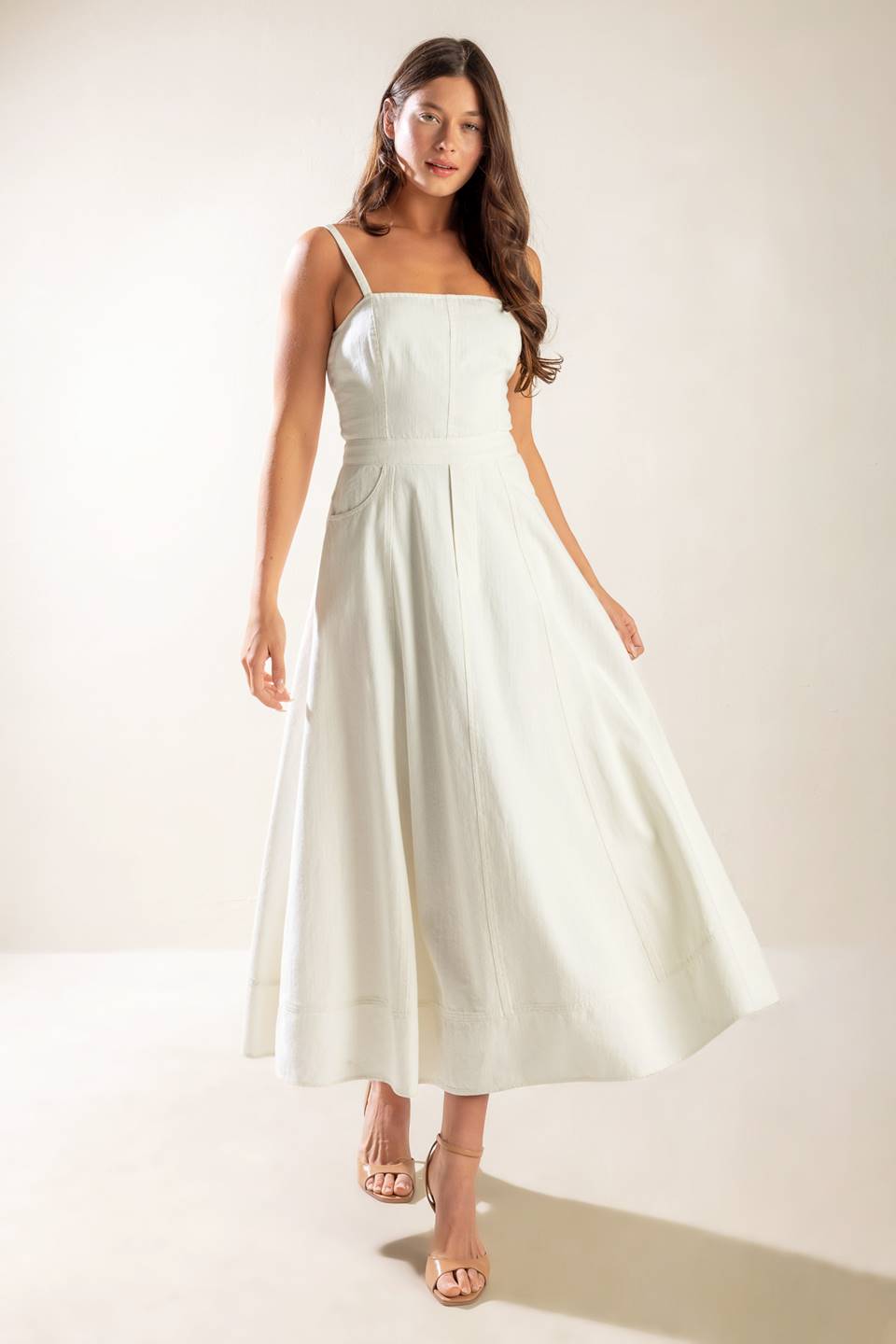 A solid white woven midi dress featuring straight neckline, straps, side pockets, circle skirt, bare back with tie and zipper closure.