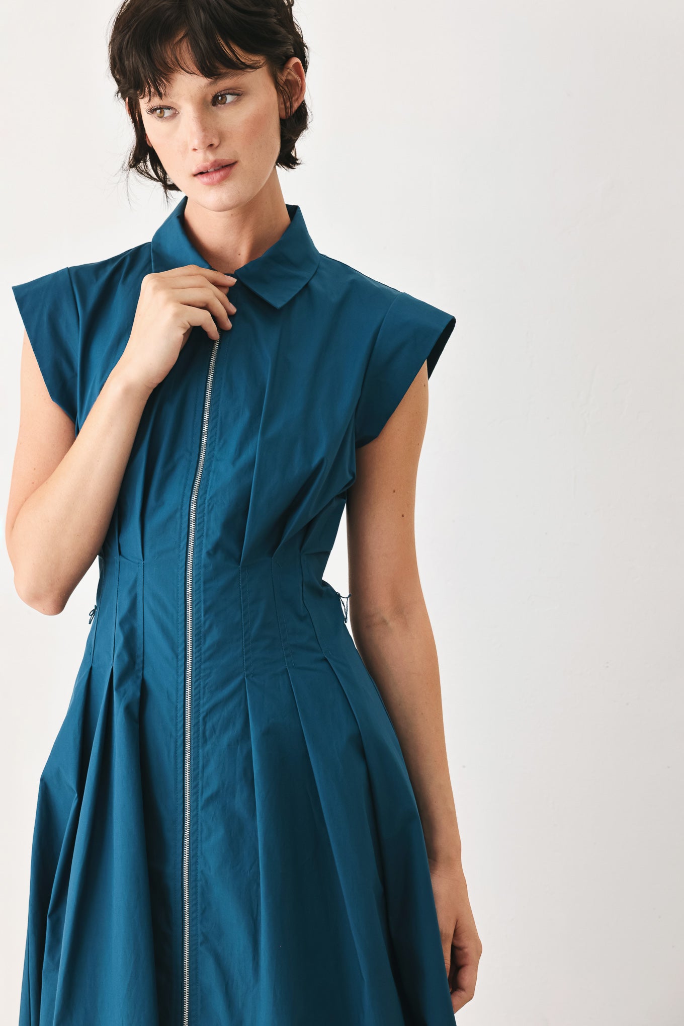 Woman wearing a teal midi dress featuring collar, short sleeve, front zipper closure and self sash tie | FREEMARKET