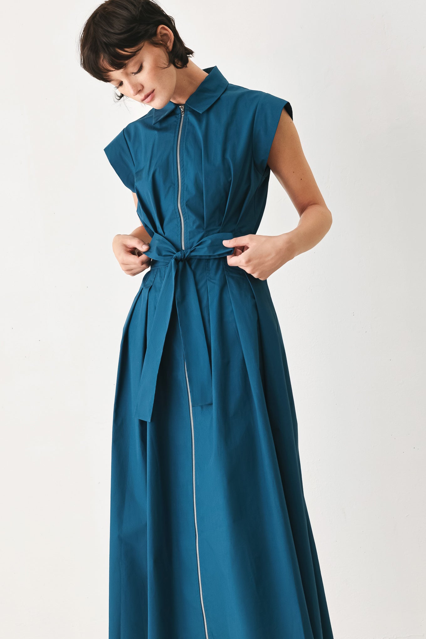 Woman wearing a teal midi dress featuring collar, short sleeve, front zipper closure and self sash tie | FREEMARKET