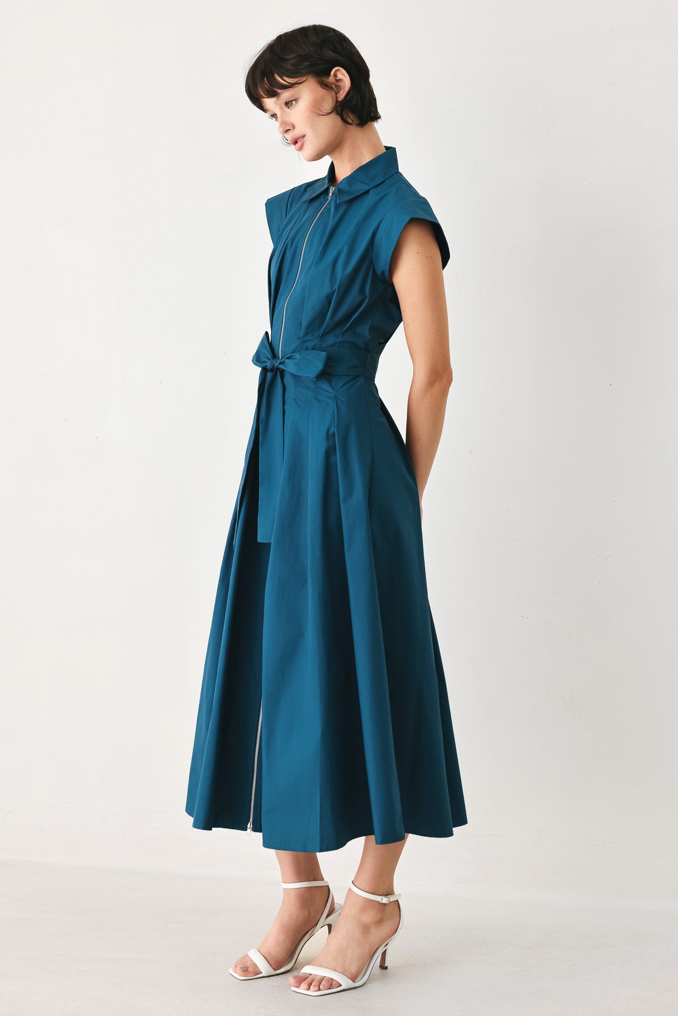 Woman wearing a teal midi dress featuring collar, short sleeve, front zipper closure and self sash tie | FREEMARKET