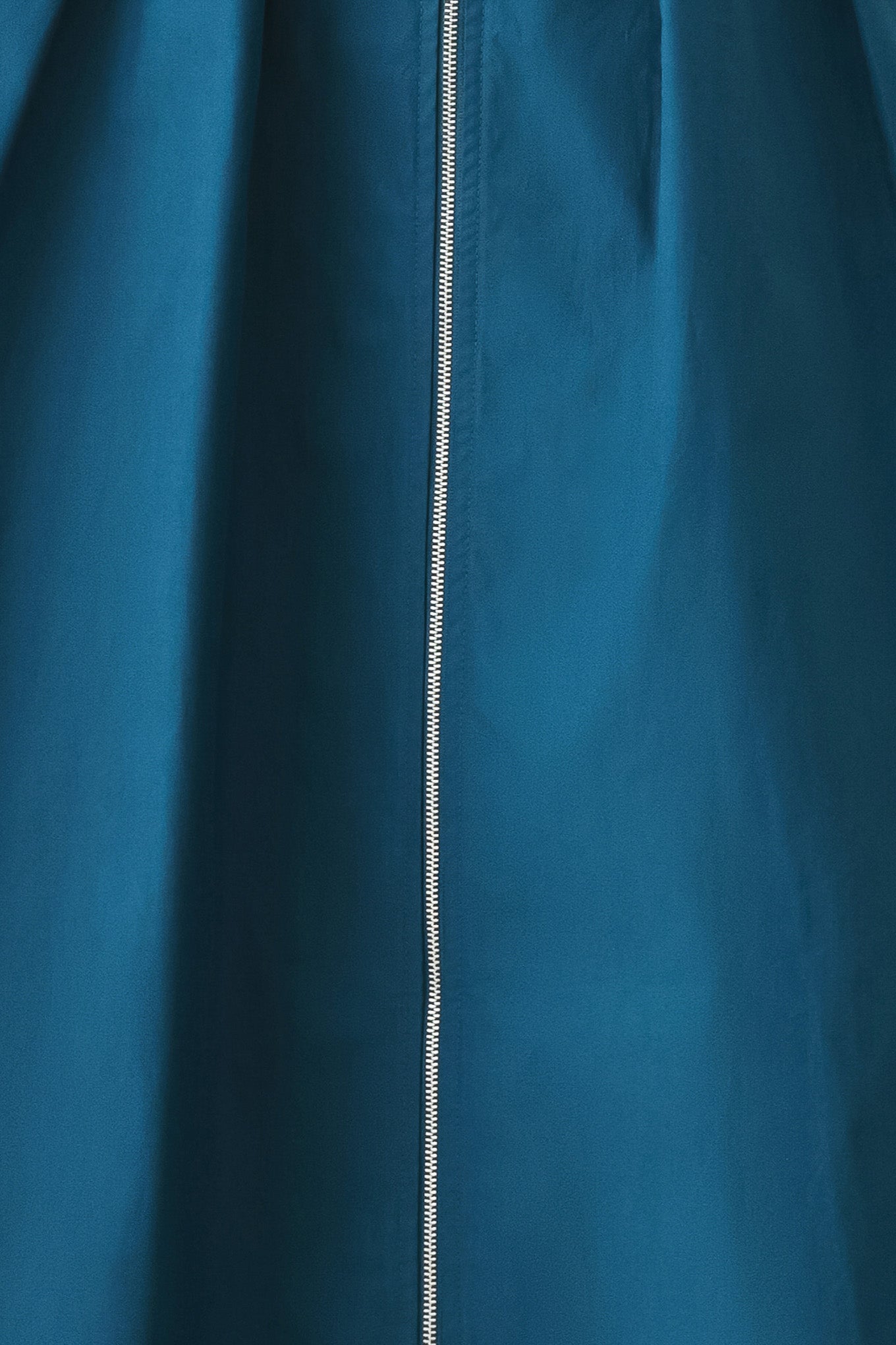 Close-up of a teal blue fabric with a zipper running vertically.