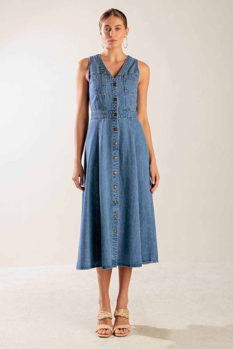 A washed denim midi dress featuring V neckline, sleeveless, button down and A line skirt