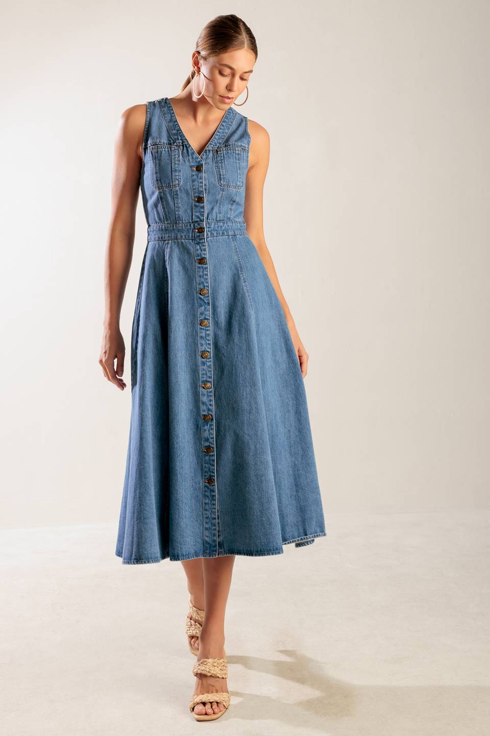 A washed denim midi dress featuring V neckline, sleeveless, button down and A line skirt