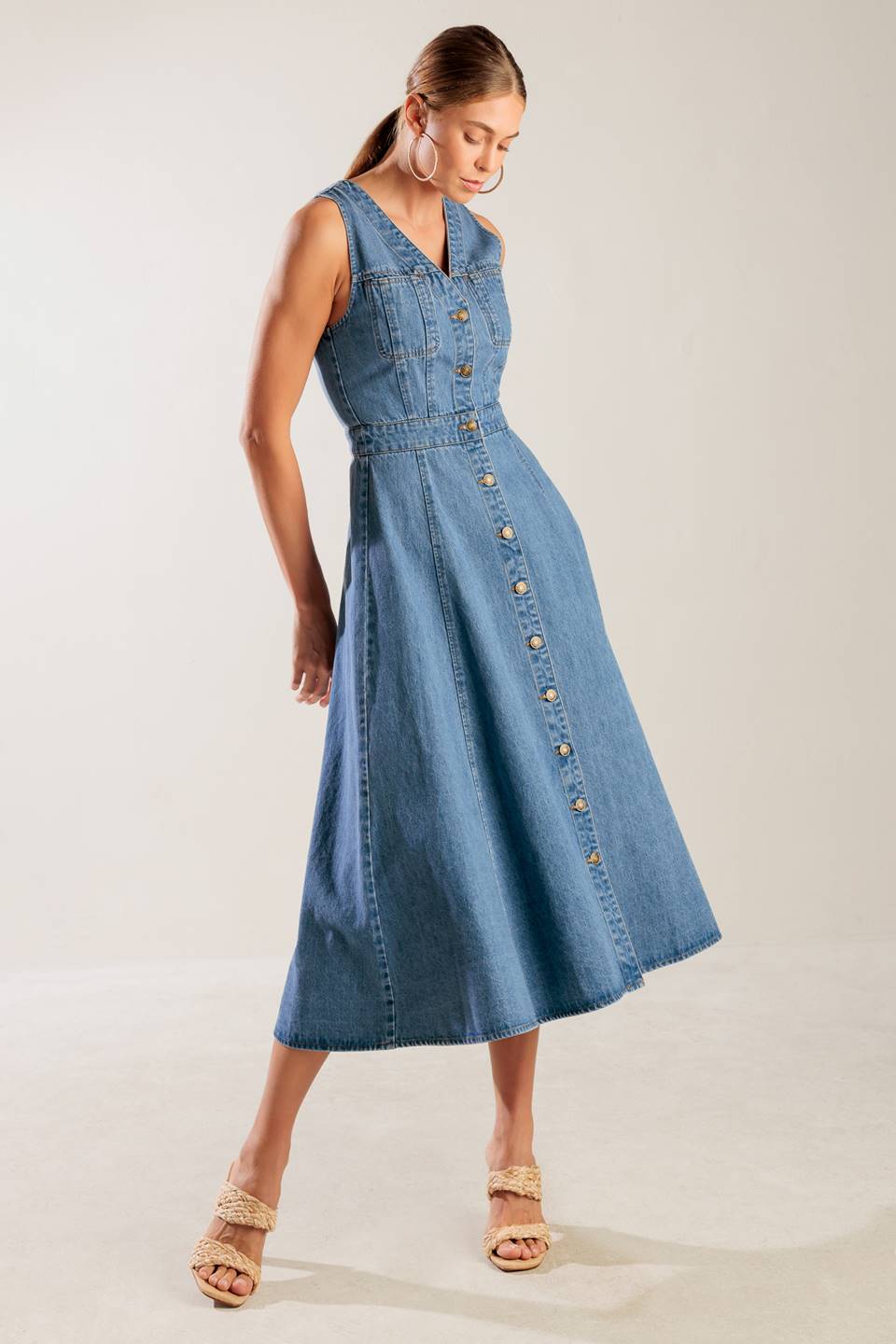 A washed denim midi dress featuring V neckline, sleeveless, button down and A line skirt