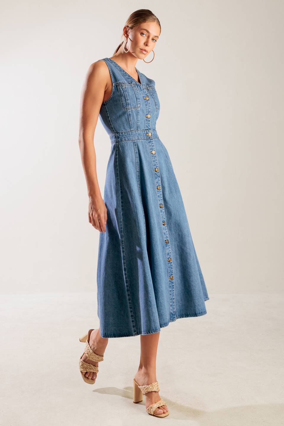 A washed denim midi dress featuring V neckline, sleeveless, button down and A line skirt