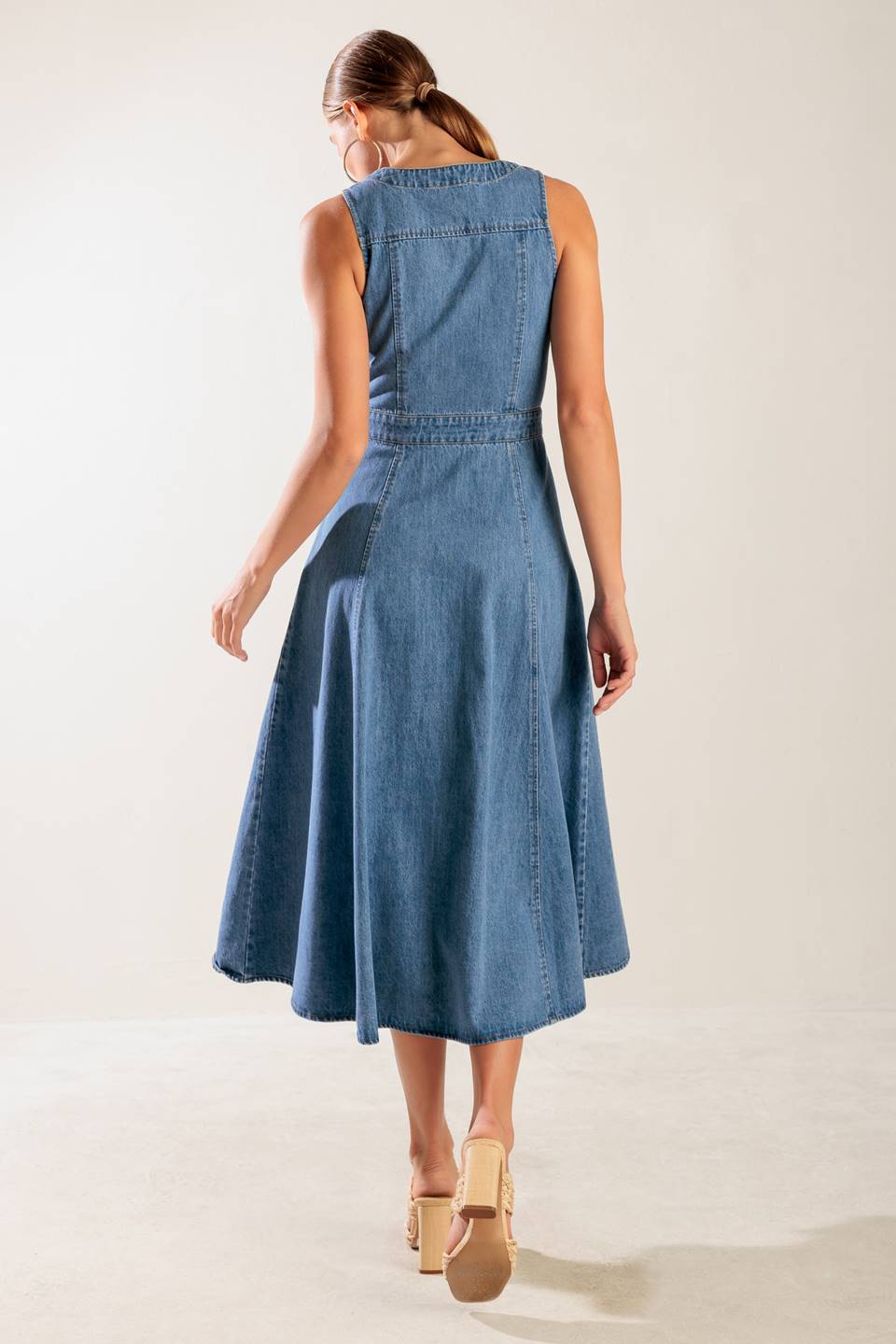 A washed denim midi dress featuring V neckline, sleeveless, button down and A line skirt