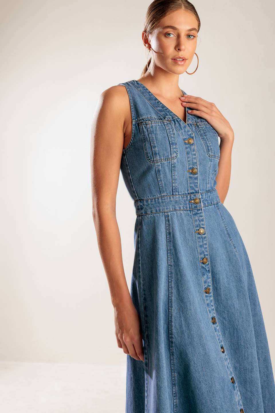 A washed denim midi dress featuring V neckline, sleeveless, button down and A line skirt