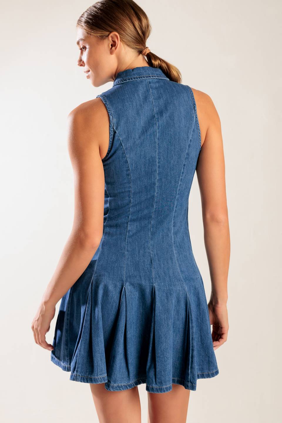 A washed denim mini dress featuring collar, button down, fitted waist and inverted pleats