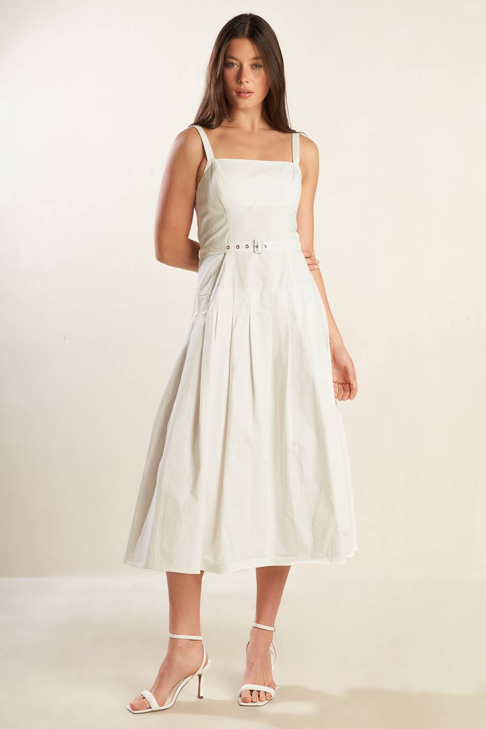 A solid white woven midi dress featuring straight neckline, straps, drop waist, self belt, box pleat and back zipper closure.