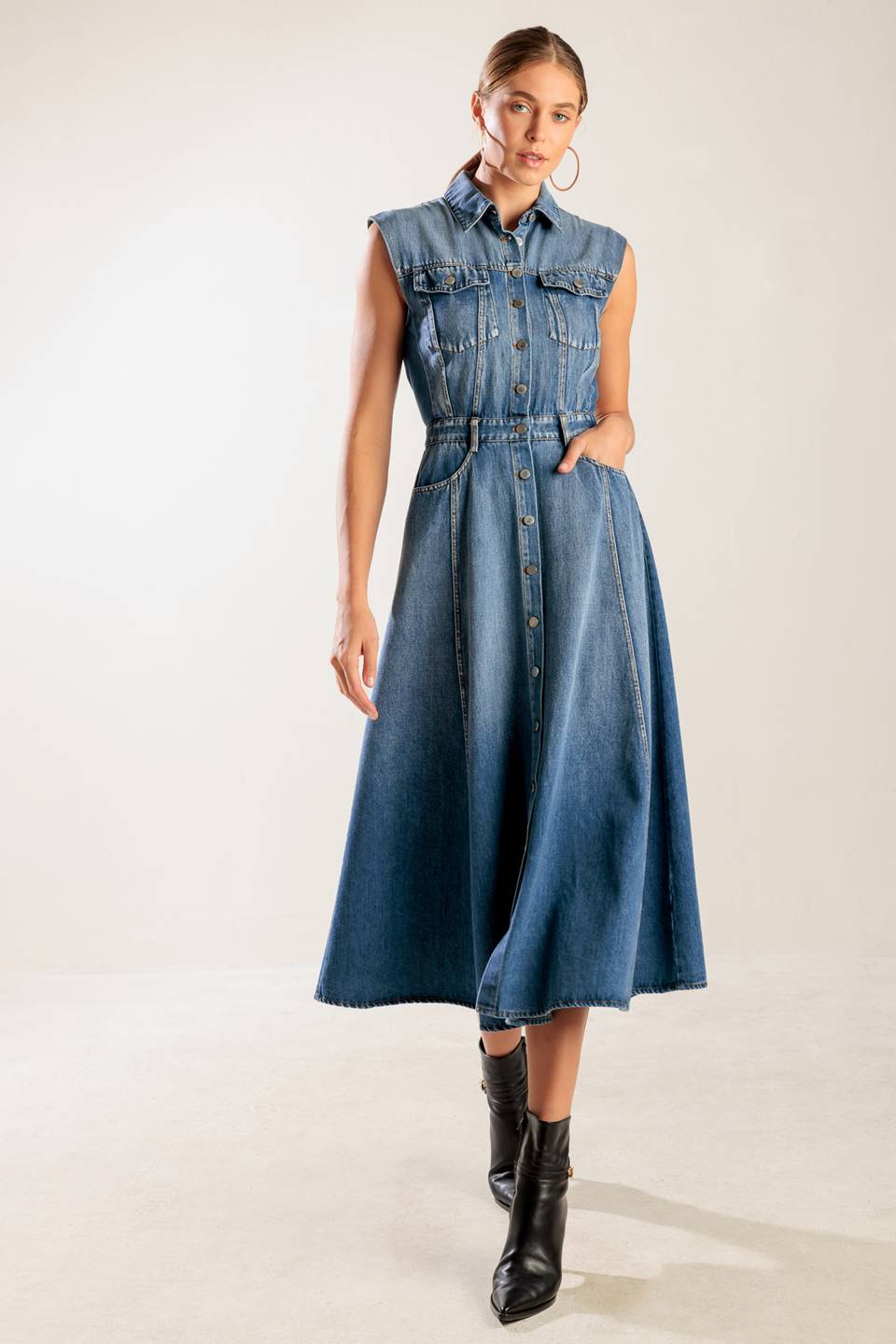 A washed denim midi dress featuring collar, sleeveless, button down, pockets and A line skirt