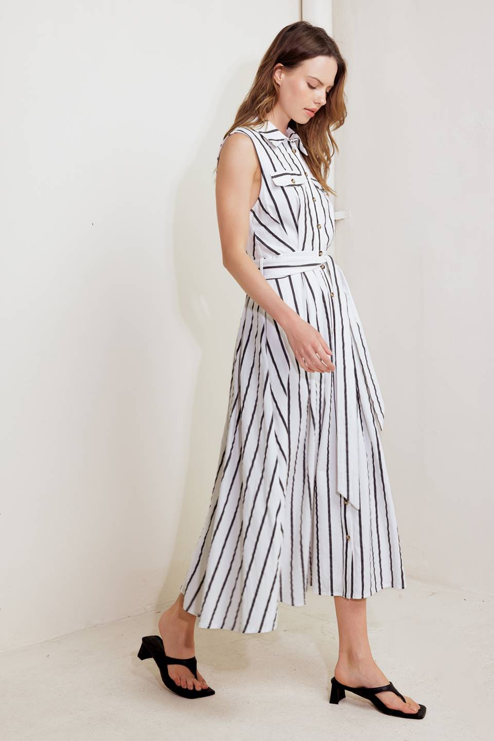 A striped woven midi dress featuring collar, sleeveless, button down, front pocket, self sash tie and full circle skirt