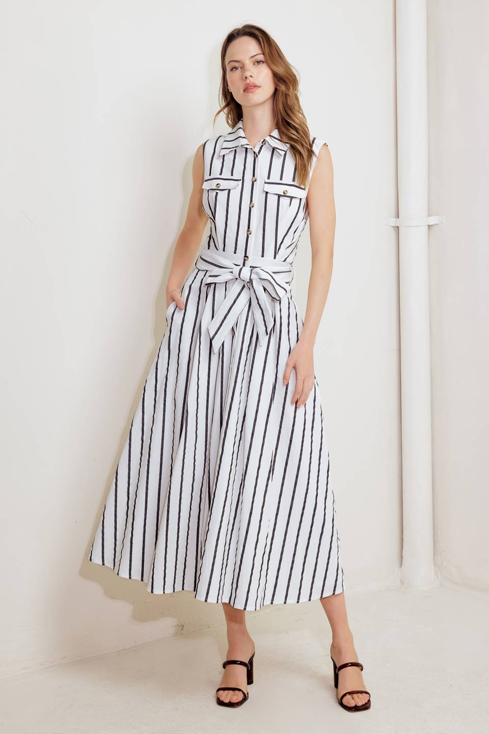 A striped woven midi dress featuring collar, sleeveless, button down, front pocket, self sash tie and full circle skirt