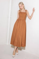 A solid woven midi dress featuring straight neckline, straps, side smocking, self sash tie and full skirt.