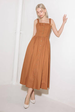A solid woven midi dress featuring straight neckline, straps, side smocking, self sash tie and full skirt.