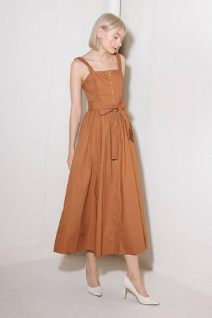A solid woven midi dress featuring straight neckline, straps, side smocking, self sash tie and full skirt.