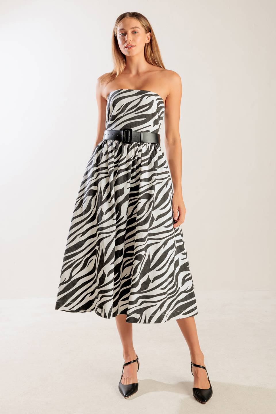 A strapless, black and white, zebra print woven midi dress featuring contrasting belt, side pockets, full skirt, and back zipper closure