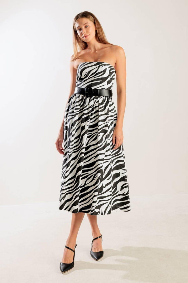 A strapless, black and white, zebra print woven midi dress featuring contrasting belt, side pockets, full skirt, and back zipper closure