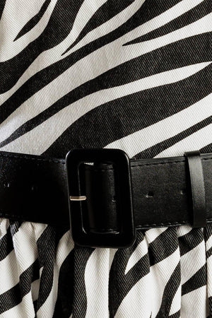 A strapless, black and white, zebra print woven midi dress featuring contrasting belt, side pockets, full skirt, and back zipper closure