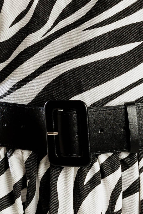A strapless, black and white, zebra print woven midi dress featuring contrasting belt, side pockets, full skirt, and back zipper closure