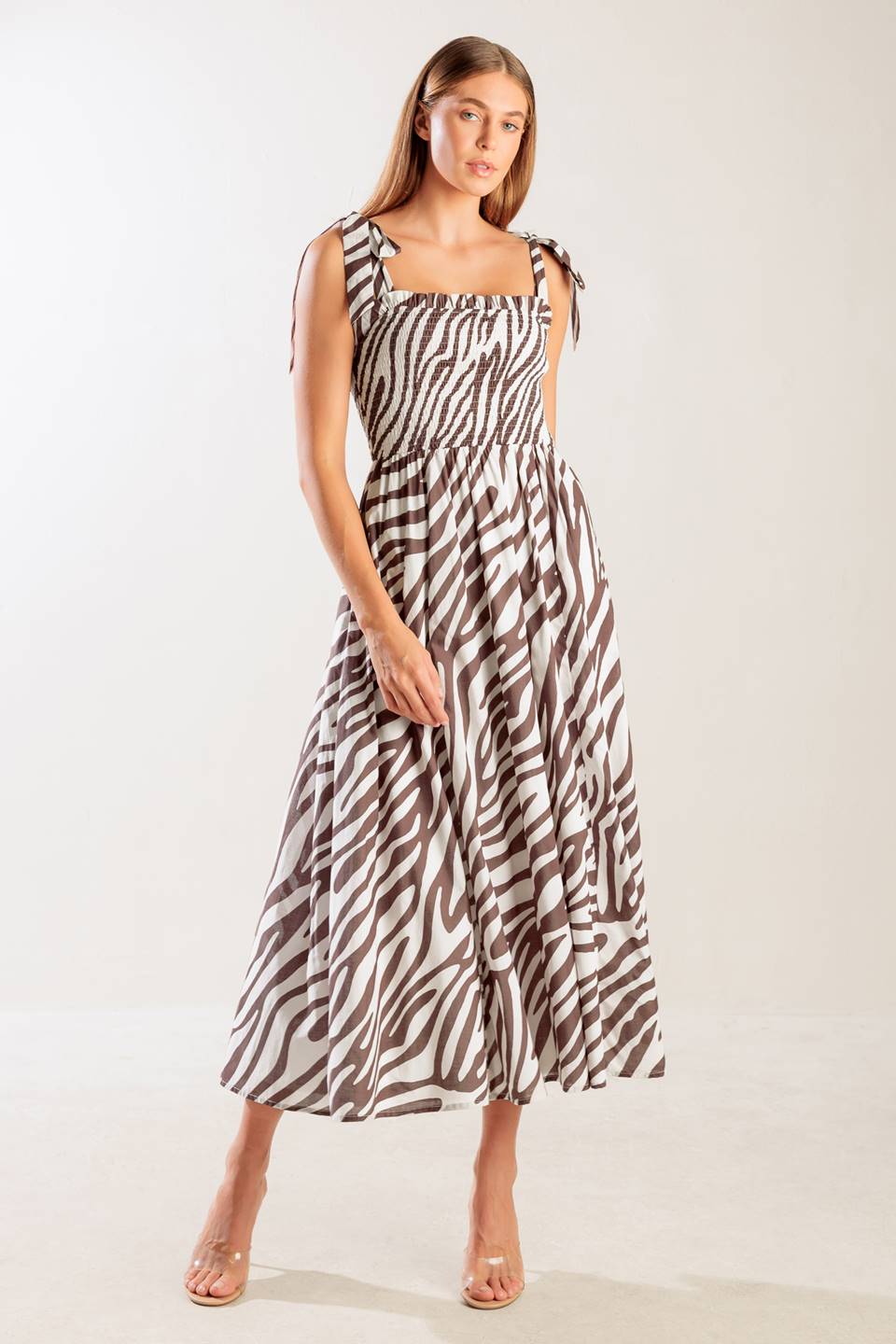 A printed woven midi dress featuring straight neckline with ruffled edge, shoulder tie, smocked bodice and full skirt