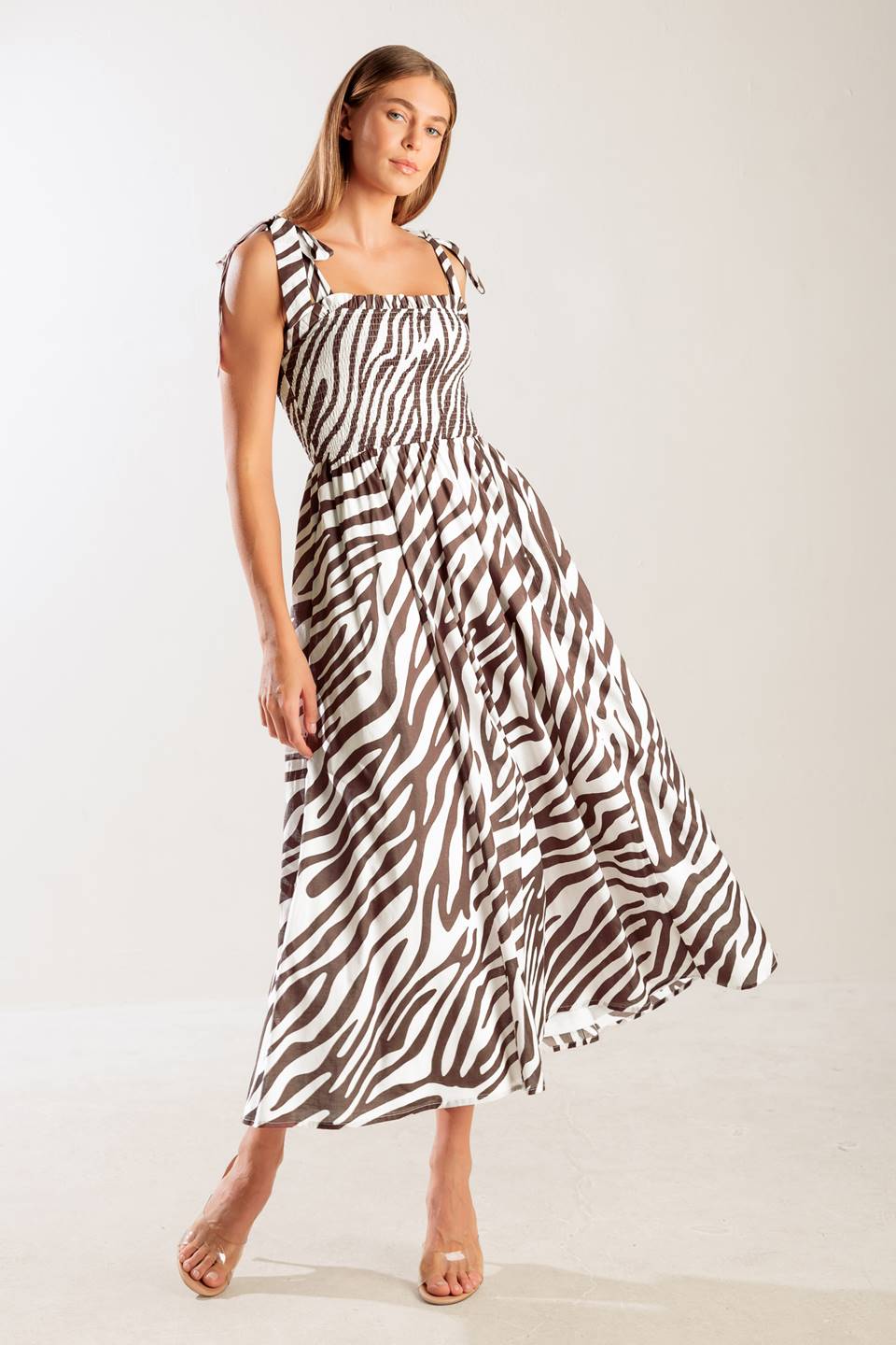 A printed woven midi dress featuring straight neckline with ruffled edge, shoulder tie, smocked bodice and full skirt