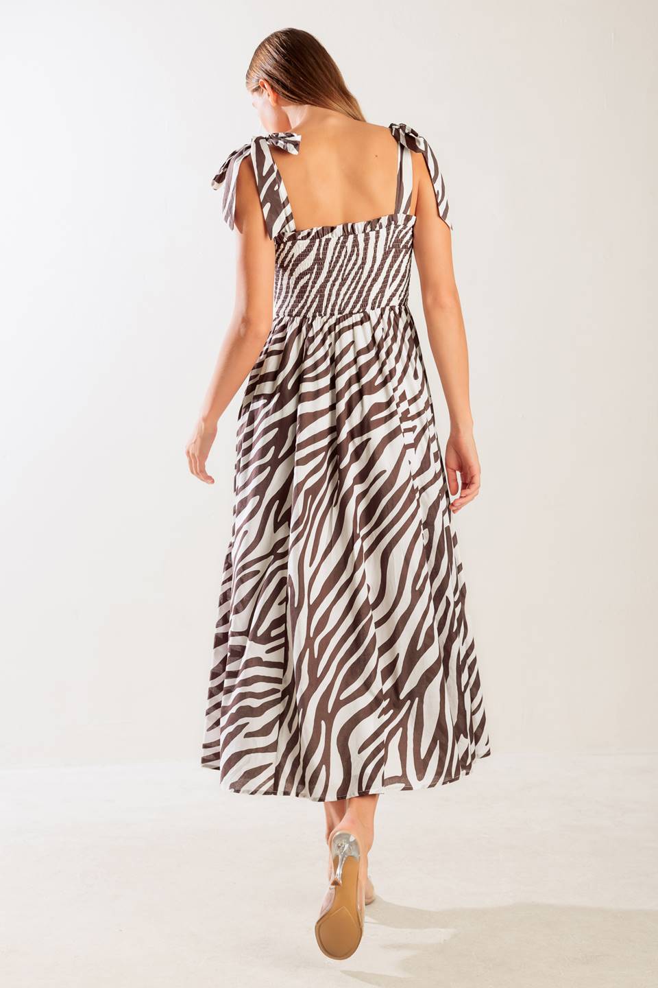 A printed woven midi dress featuring straight neckline with ruffled edge, shoulder tie, smocked bodice and full skirt